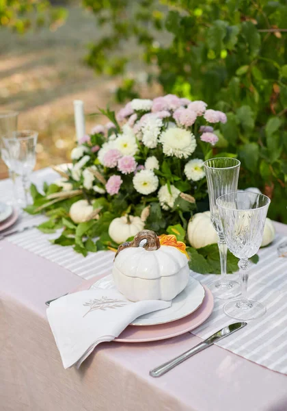 Table setting with beautiful autumn decorand with white mini pumpkins and crystal glasses for Thanksgiving Day or Halloween