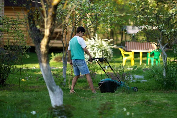 Человек стрижет газон газонокосилкой — стоковое фото