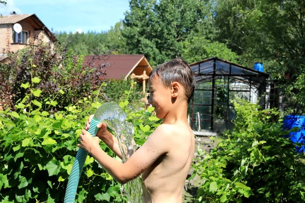 O menino com água salpicada no dia quente de verão ao ar livre — Fotografia de Stock