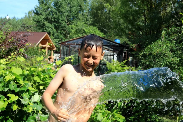 Хлопчик з бризкою води в спекотний літній день на відкритому повітрі — стокове фото