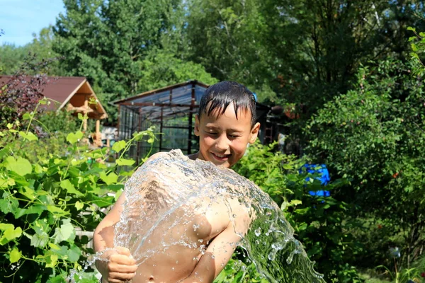 Chłopiec z Splash Water w bardzo gorącym letnim dniu na świeżym powietrzu — Zdjęcie stockowe