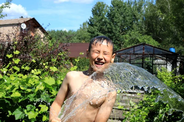 Pojken med stänk vatten i mycket varm sommardag utomhus — Stockfoto