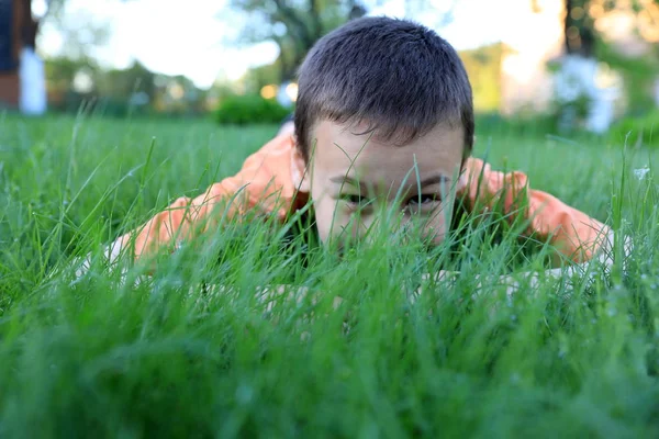 O menino se esconde na grama verde — Fotografia de Stock