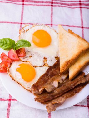 Pastırma ve kızarmış yumurta kahvaltı. Gevrek tost dilim dilimlenmiş kiraz domates, fesleğen yaprakları ile beyaz tabakta servis.