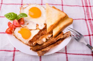 Pastırma ve kızarmış yumurta kahvaltı. Gevrek tost dilim dilimlenmiş kiraz domates, fesleğen yaprakları ile beyaz tabakta servis.