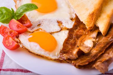 Pastırma ve kızarmış yumurta kahvaltı. Gevrek tost dilim dilimlenmiş kiraz domates, fesleğen yaprakları ile beyaz tabakta servis.