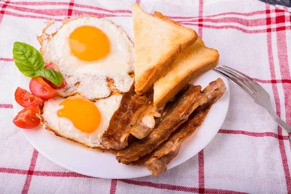 Pastırma ve kızarmış yumurta kahvaltı. Gevrek tost dilim dilimlenmiş kiraz domates, fesleğen yaprakları ile beyaz tabakta servis.
