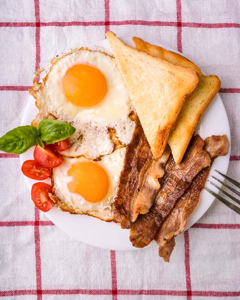 Pastırma ve kızarmış yumurta kahvaltı. Gevrek tost dilim dilimlenmiş kiraz domates, fesleğen yaprakları ile beyaz tabakta servis.
