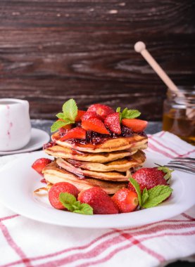 Lezzetli Amerikan krep ile taze çilek, reçel ve yaprakları nane. Bir beyaz tabakta. Sağlıklı kahvaltı.