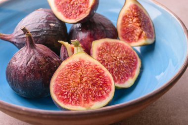 Taze incir. Bütün incir ve mavi seramik kase dilimlenmiş içinde yarım incir. Görünümü kapatın.