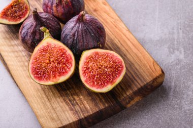 Taze incir. Bütün incir ve ahşap kesme tahtası üzerinde içinde dilimlenmiş yarım incir.