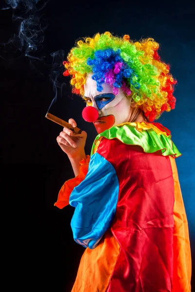 Payaso loco sobre fondo negro. Mujer está fumando cigarro . — Foto de Stock