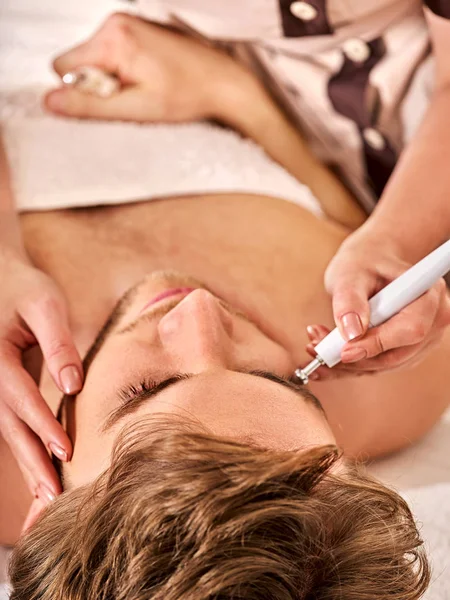 Facial massage at beauty salon. Electric stimulation man skin care.