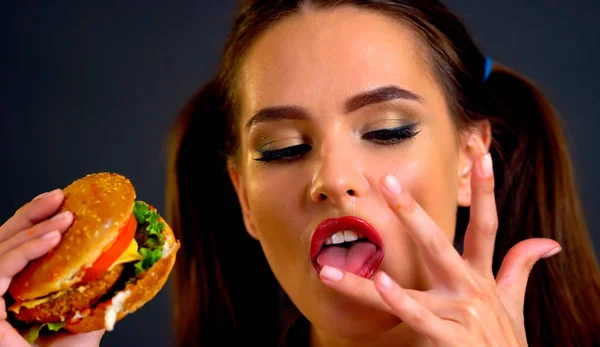 Γυναίκα τρώει χάμπουργκερ. Το κορίτσι θέλει να τρώνε fast food. — Φωτογραφία Αρχείου