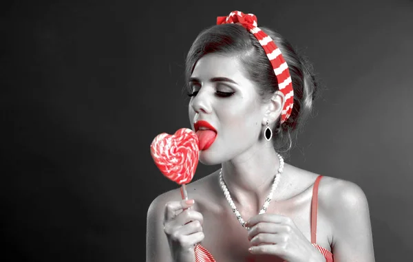 Vrouw eten lollies. Meisje in pin-up stijl houdt gestreepte snoep. — Stockfoto