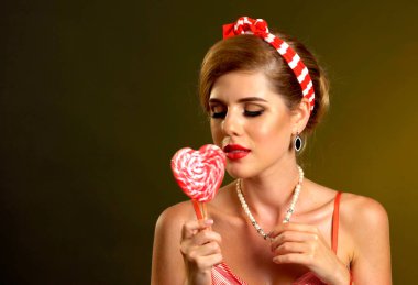 Lolipop yiyen kadın. Pin-up tarzı kız tutun çizgili şeker.