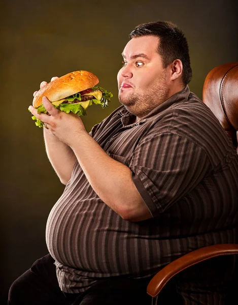 Fat man eating fast food hamberger. Breakfast for overweight person. Royalty Free Stock Images