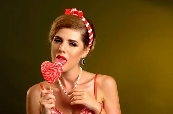 Kvinna äta klubbor. Flicka i pin-up stil håll randig godis. — Stockfoto