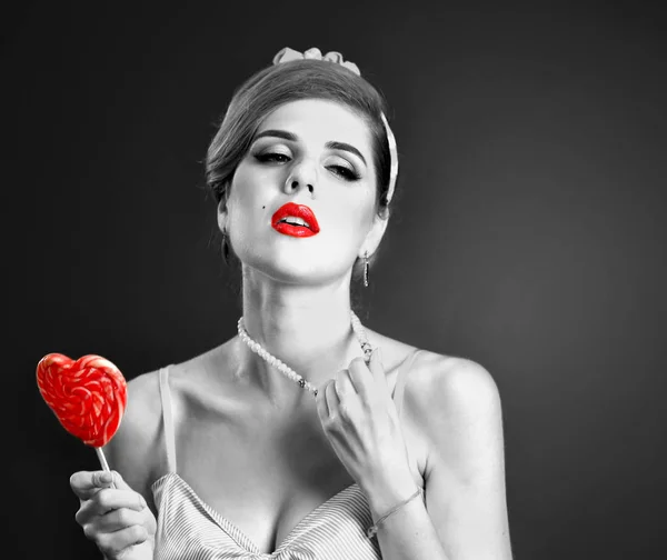 Жінка їсть льодяники. Дівчина в стилі пін-ап тримає смугасті цукерки . — стокове фото
