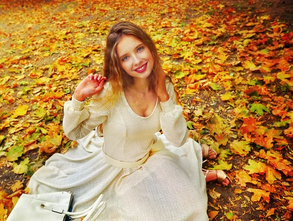 Outono vestido de moda mulher sentado queda deixa parque da cidade ao ar livre . — Fotografia de Stock