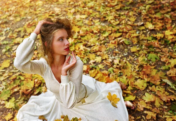 Outono vestido de moda mulher sentado queda deixa parque da cidade ao ar livre . — Fotografia de Stock