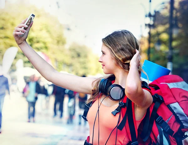 Touristin mit Rucksack und Kopfhörer macht Selfies auf Smartphone — Stockfoto