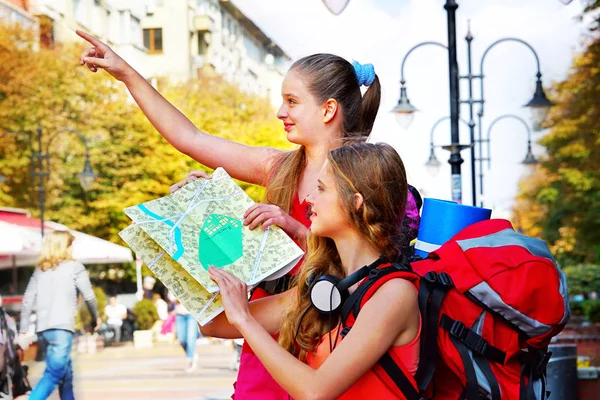 Holky cestovatelů s batohem, hledají způsob turistické papírovou mapu — Stock fotografie