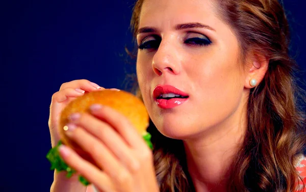 Vrouw beet hamburger en knipogen. Gelukkig student eten broodjeslunch. — Stockfoto