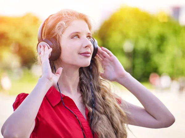Chica en auriculares escucha música en la ciudad —  Fotos de Stock