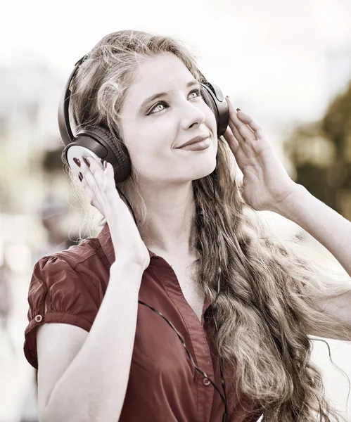 Menina em fones de ouvido ouve música na cidade. Preto e branco — Fotografia de Stock