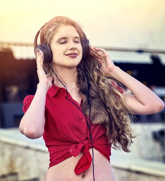 Menina em fones de ouvido ouve música na cidade — Fotografia de Stock