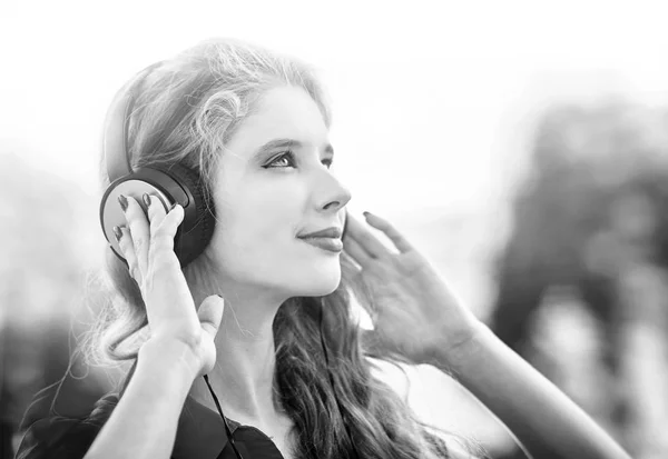 Menina em fones de ouvido ouve música na cidade. Preto e branco — Fotografia de Stock