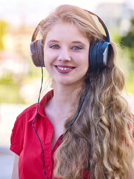 Chica en auriculares escucha loco por la música mp3 en la ciudad —  Fotos de Stock