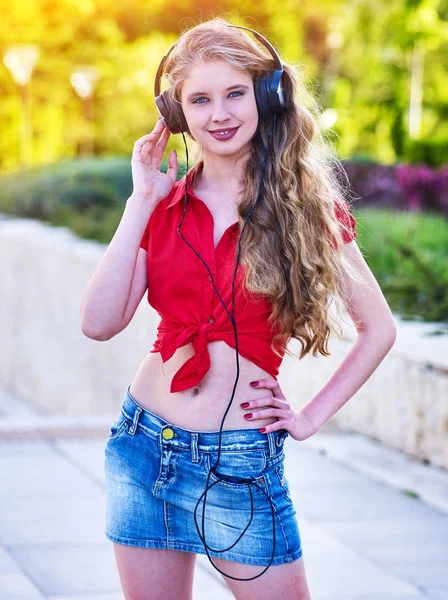 Girl in headphones and denim listens to music with closed eyes — Stock Photo, Image