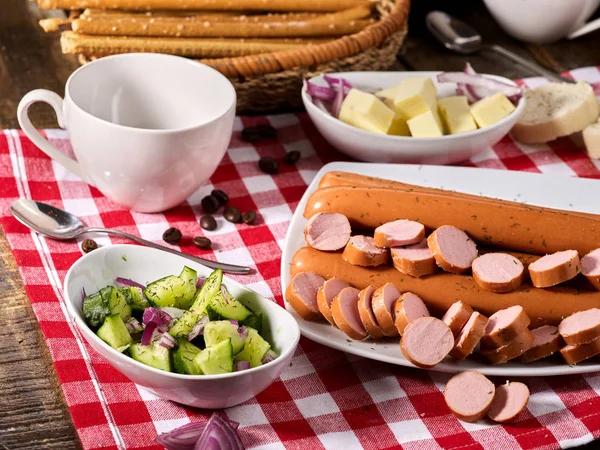 Porción de salchicha con baguette en la mesa en tela a cuadros — Foto de Stock