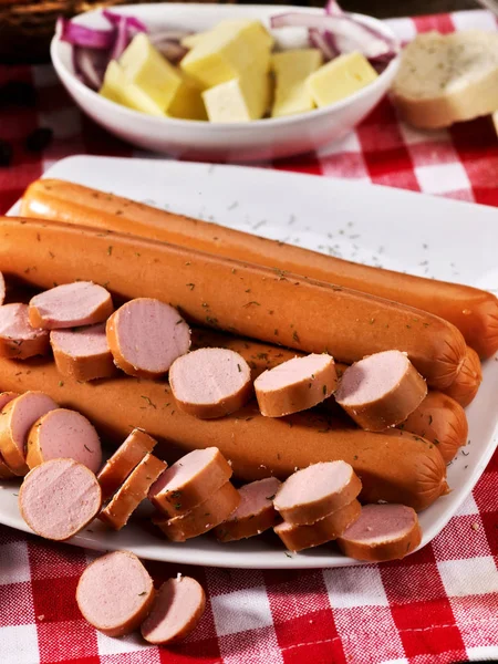 Porción de salchicha con baguette en la mesa en tela a cuadros — Foto de Stock