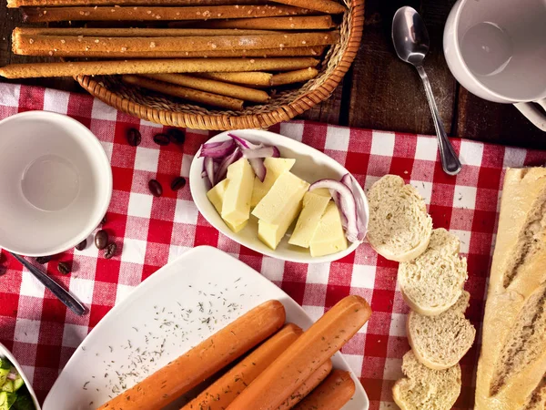 Porción de salchicha con baguette en la mesa en tela a cuadros — Foto de Stock
