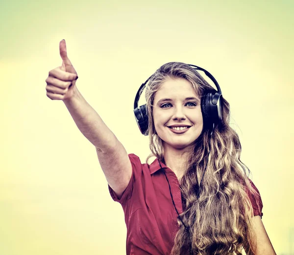 Estudiante chica en auriculares escuchar música mostrar pulgar hacia arriba —  Fotos de Stock