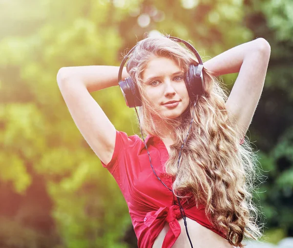 Estudiante chica con auriculares mochila escuchar música sobre hierba verde —  Fotos de Stock