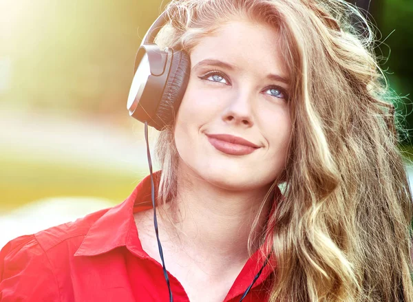 Estudante menina com mochila fone de ouvido ouvir música na grama verde — Fotografia de Stock