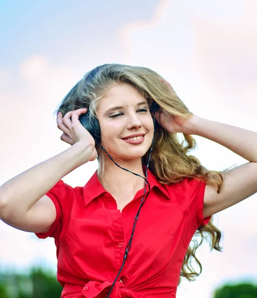 Estudante menina com mochila fone de ouvido ouvir música na grama verde — Fotografia de Stock