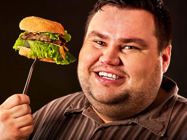 Cara de hombre gordo come hamburguesa en tenedor —  Fotos de Stock