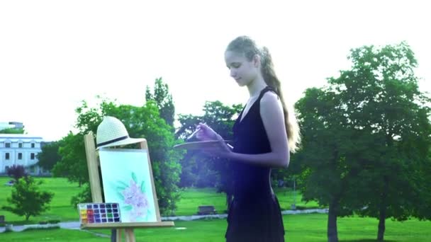Chica dibuja en plein aire en hierba verde en el parque de la ciudad — Vídeos de Stock