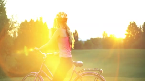 Chica en casco en bicicleta en el parque con horizonte de la ciudad — Vídeos de Stock