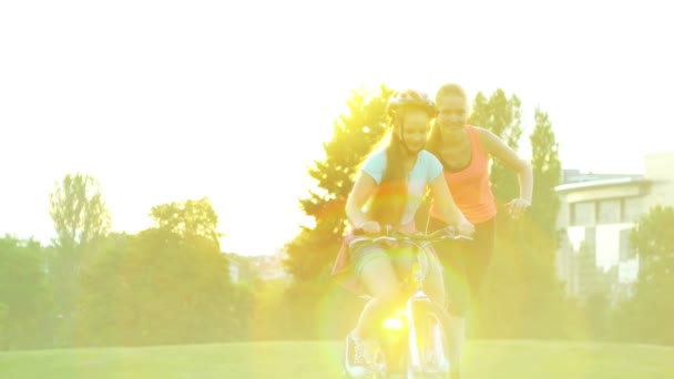 Τα παιδιά στο κράνος ποδήλατο διδάσκουν ποδήλατο βόλτα στο καλοκαιρινό πάρκο — Αρχείο Βίντεο