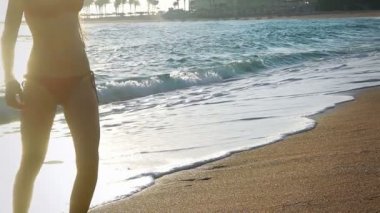 Plaj kızı denizden palmiye ağaçlarıyla çıkıyor.