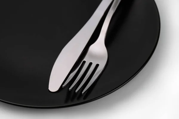 黒い皿の上のフォークとナイフを閉じる — ストック写真