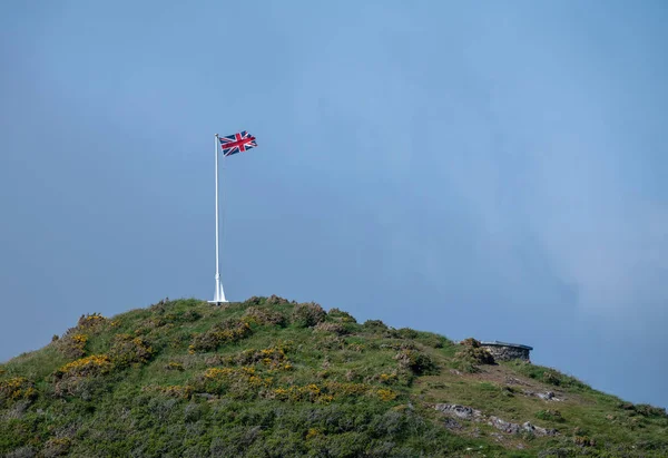 Vlajkou a stožár na ostrohu proti modré obloze — Stock fotografie