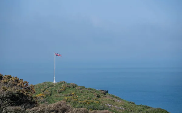 Bandiera dell'Unione e asta di bandiera sul promontorio sopra il mare — Foto Stock