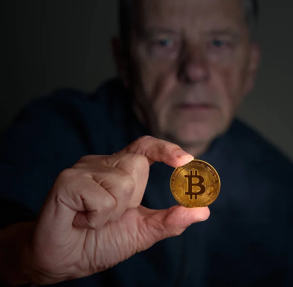 Senior-Mann untersucht Bitcoin auf Waffenlänge — Stockfoto